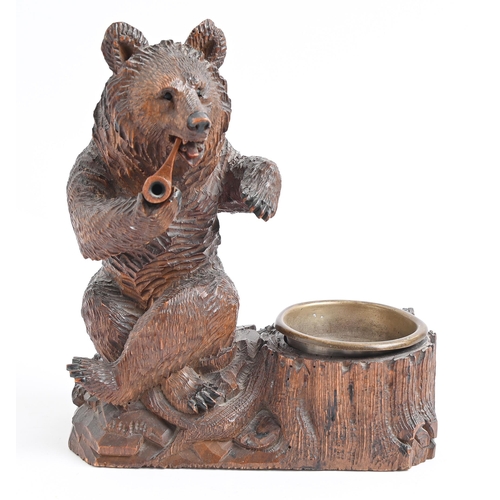 1027 - A Swiss anthropomorphic limewood  ashtray in the form of a bear smoking a pipe, c1900, 23c... 