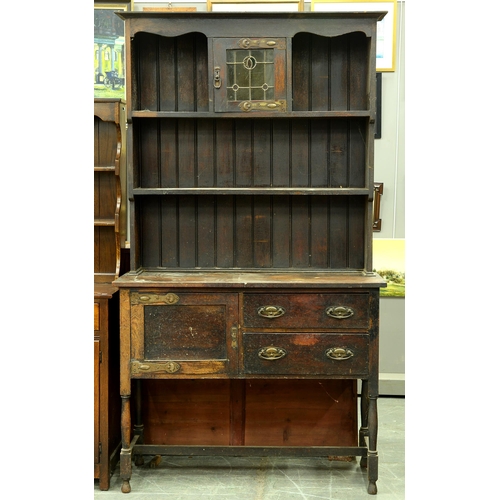 1194 - An Edwardian oak dresser, the panelled rack with central cupboard with leaded glass door, 216cm h; 4... 