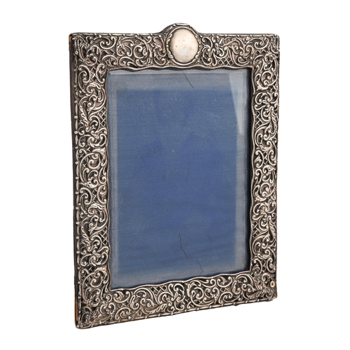 553 - An Edwardian silver photograph frame, the die stamped mount with C-scrolls and trellis, 28cm h, by H... 