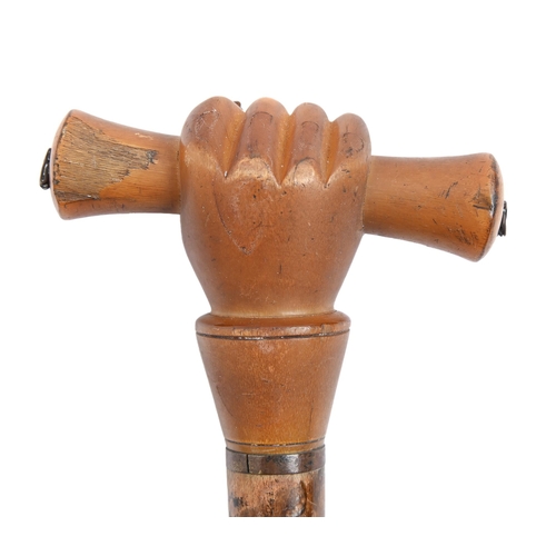 825 - A cane or parasol handle, 19th c,  the pommel carved as a baton in a clenched fist, 20cm h... 