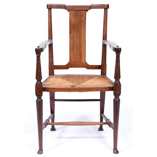 1249 - An Arts and Crafts walnut elbow chair, early 20th c, rush seated, on turned legs united by stretcher... 