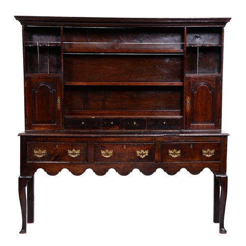 417 - A George III oak dresser, the cavetto cornice above two-shelf boarded rack with spice cupboards with... 