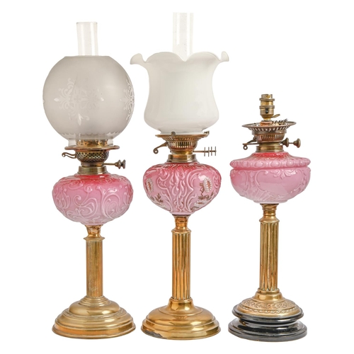 414 - Three Victorian brass oil lamps,  of columnar form, each with scroll moulded pink glass fount (one e... 