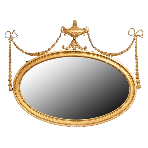 842 - An Edwardian oval neo classical giltwood and composition mirror, surmounted by an urn and festoons, ... 