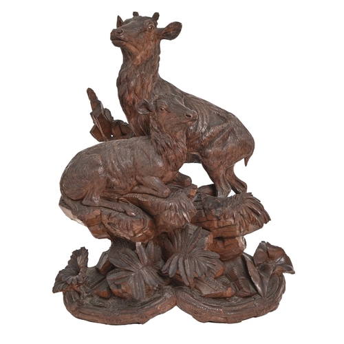 267 - A Swiss carved limewood sculpture of two mountain deer, 19th / 20th c, on rocks and vegetation, 54cm... 