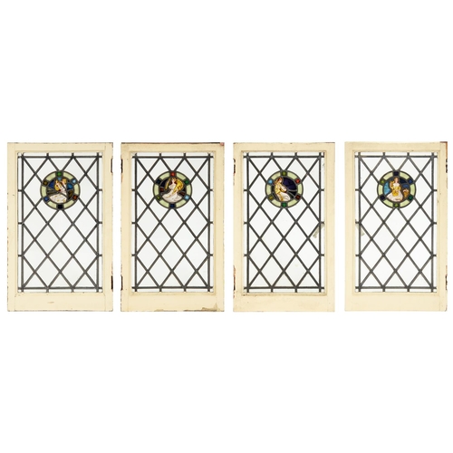 299 - A set of four Arts & Crafts stained glass window lights, with roundels of a seated female musici... 