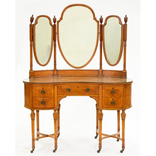 583 - An Edwardian serpentine satinwood dressing table, c1910, with carved finials and three oval or shiel... 