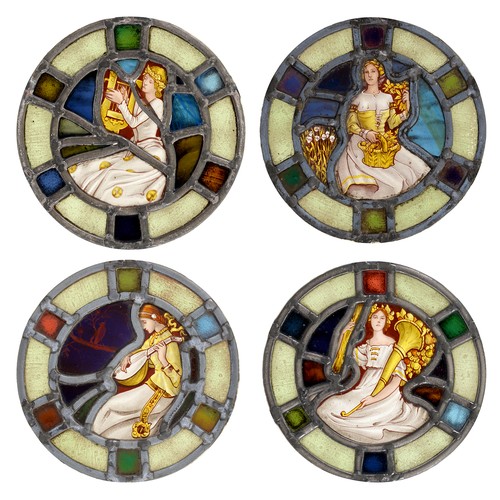 299 - A set of four Arts & Crafts stained glass window lights, with roundels of a seated female musici... 