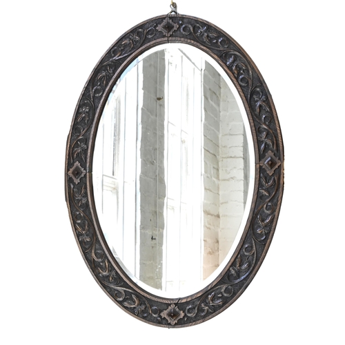 1154 - An oval mirror, with bevelled plate in carved oak frame, 89 x 64cm