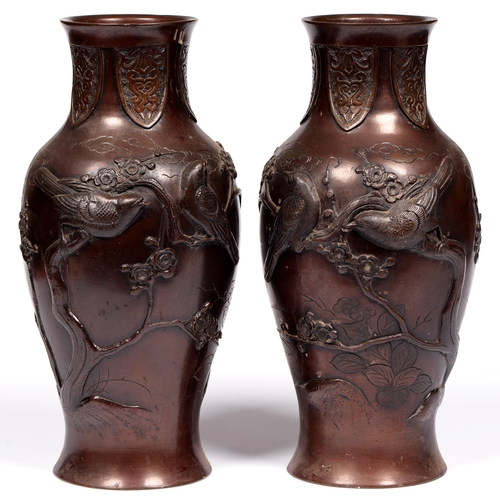 804 - A pair of Japanese bronze vases, Meiji period, decorated in relief with birds on prunus, russet pati... 