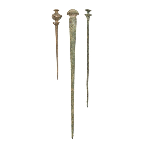 1038 - Antiquities. Three Luristan bronze pins, 1000-800 BC, 16-29.5cm l