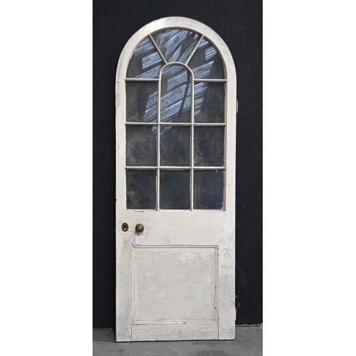 1386 - A Victorian arched painted timber door, with glass lights and lower panel, original steel rim lock a... 