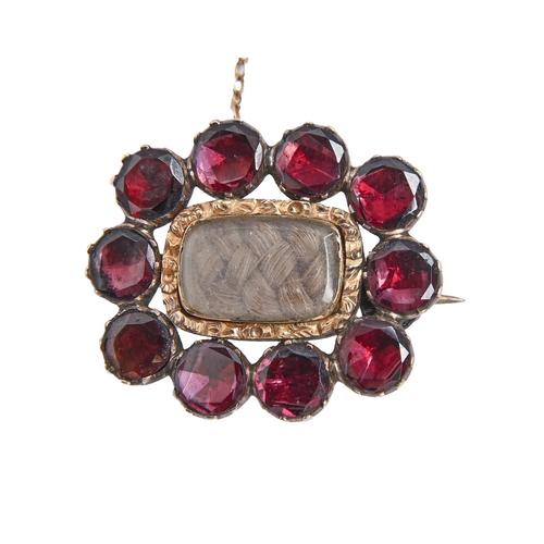 261 - An English foiled garnet mourning brooch, c1840, inset plaited hair, 24mm, 4.2g