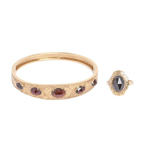 152 - An engraved gold bangle, late 20th c, in Victorian style, set with five graduated oval garnets, 64mm... 