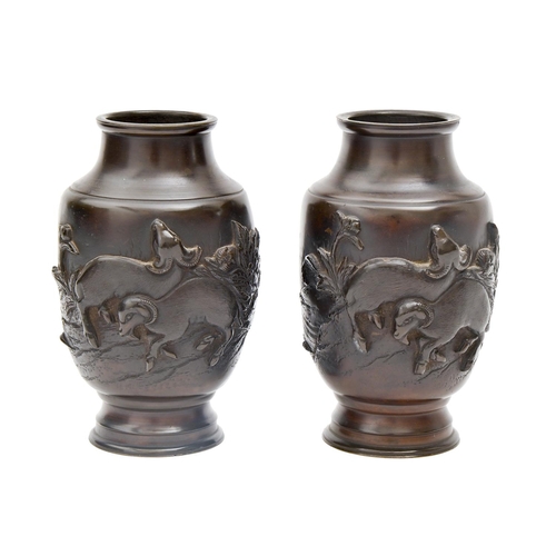 799 - A pair of Japanese bronze vases, Meiji period, cast in relief and chiselled with two goats in a cont... 