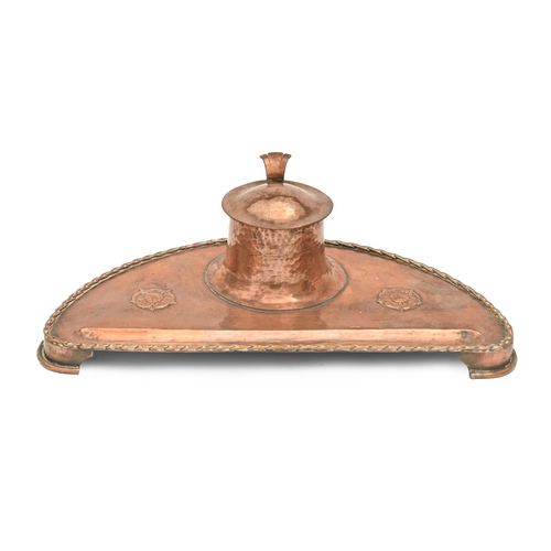 810 - An English Arts and Crafts copper inkwell, c1910, on bracket feet, 25cm l