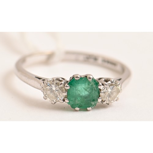 184 - An emerald and diamond ring, the step cut emerald flanked by round brilliant cut diamonds, in platin... 