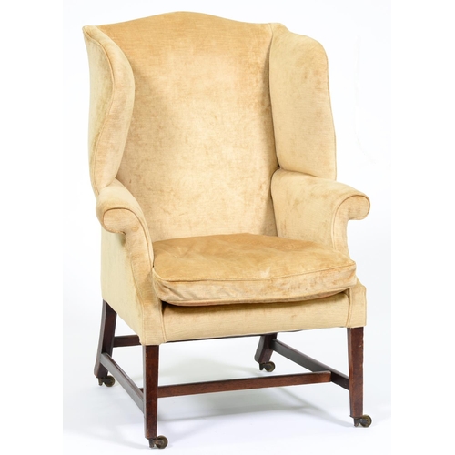 1218 - A George III mahogany wing armchair, on square legs with stretchers, brass castors