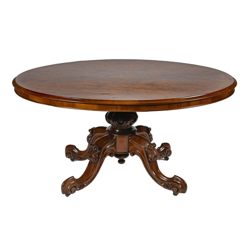 986 - A Victorian walnut loo table, with butterfly veneered oval top, on carved and scrolling quadruple le... 