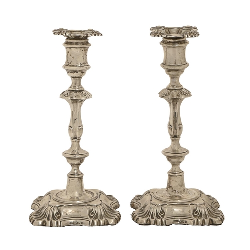 277 - A pair of George V silver candlesticks, in mid 18th c English style, on shell cornered foot, nozzles... 