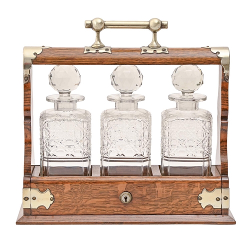 579 - An EPNS mounted oak tantalus, early 20th c, with set of three cut glass decanters and stoppers, key,... 