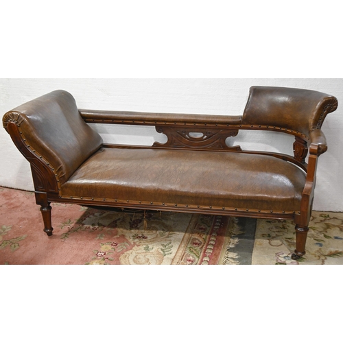 1197 - A Victorian carved mahogany couch, covered with nailed back brown leather, on turned legs and brass ... 