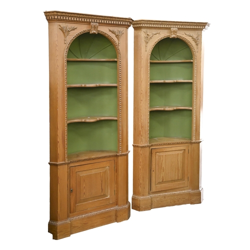 1130 - A pair of pine standing corner cabinets, 20th c, with dentil cornice and carved acanthus keystone to... 