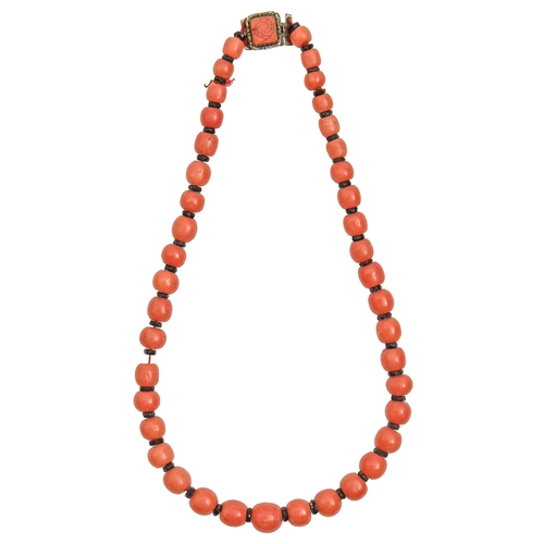 152 - An Art Deco necklace, of coral beads with black glass spacers and metal clasp, largest bead 11m... 