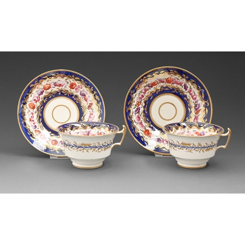 629 - A pair of English porcelain teacups and saucers, c1820, painted with trailing flowers on a blue band... 