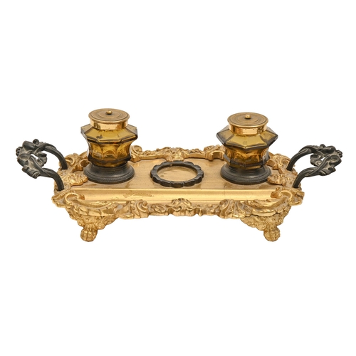 712 - A Victorian gilt and patinated brass inkstand, cast with satyr masks, retaining the pair of original... 