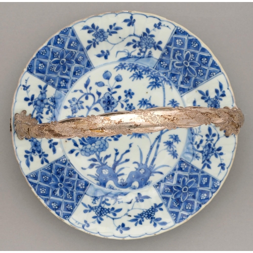 123 - A Chinese blue and white dish, Kangxi period, painted with peony and bamboo sprouting from hollow ro... 