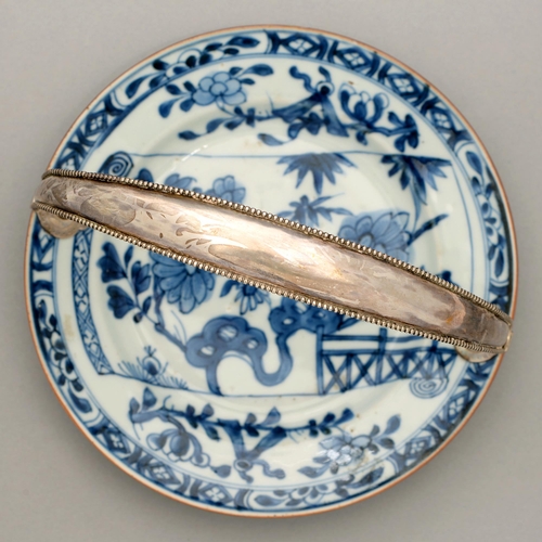 125 - A Chinese blue and white plate, 18th c, painted with a flowering plant, bamboo and fence on a scroll... 