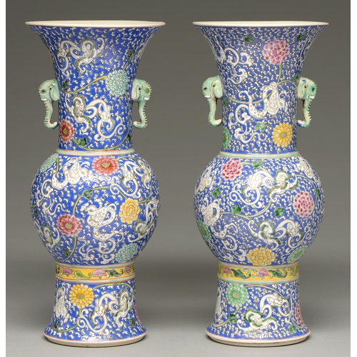 223 - A pair of Chinese blue ground famille verte vases, 20th c, of gu form with elephant head handles, en... 