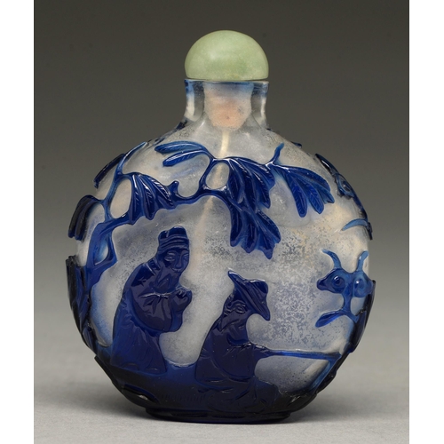 305 - A Chinese glass snuff bottle, 20th c, of semi transparent clear glass overlaid in blue and carved wi... 