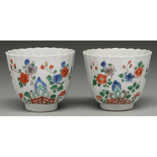 311 - Two Chinese famille verte fluted cups, Kangxi period, painted with flowering plants growing from a h... 