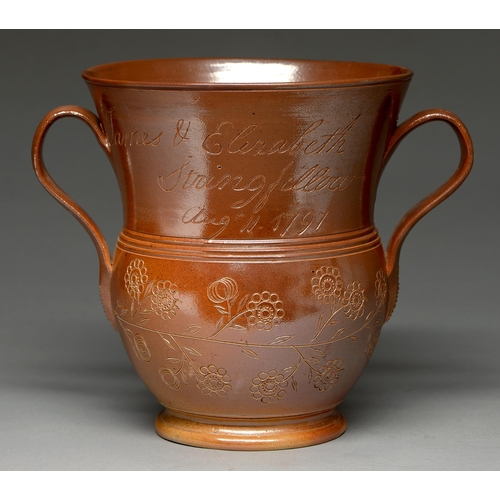 564 - A Derbyshire saltglazed brown stoneware loving cup, Chesterfield, dated 1797, the flared neck incise... 