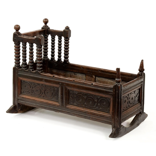 1221 - A James II oak cradle, dated 1686, with turned finials and bobbin turned gallery, the panels to the ... 