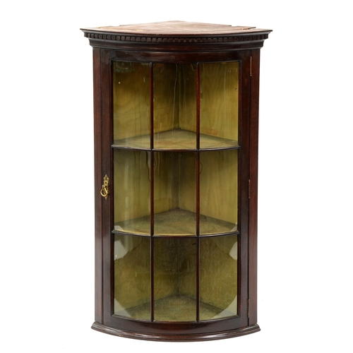 1224 - A bow fronted mahogany hanging corner cabinet, early 20th c, with dentil cornice and glazed nine pan... 