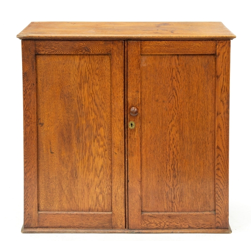 1233 - An oak cupboard, early 20th c, the interior divided into shoe compartments and others, one enclosed ... 