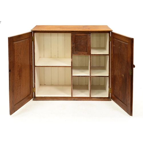 1233 - An oak cupboard, early 20th c, the interior divided into shoe compartments and others, one enclosed ... 