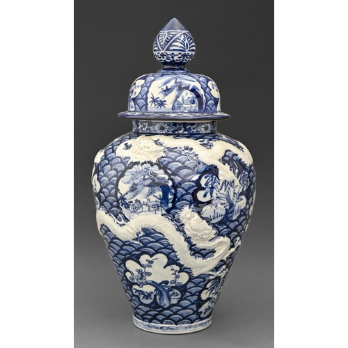 382 - A Japanese blue and white jar and cover, early 20th C, moulded with dragons and painted in underglaz... 