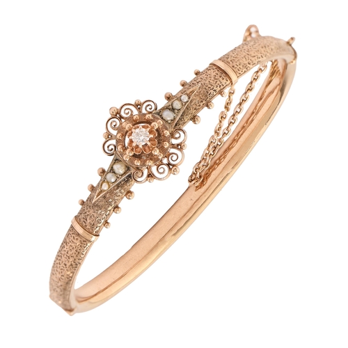 70 - A diamond and split pearl bangle, early 20th c, in gold, applied with filigree work and centred by a... 