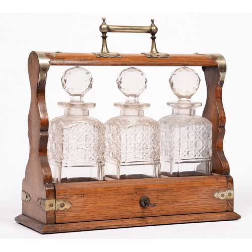 803 - An oak tantalus with three cut glass decanters, early 20th c, with key, 35cm w