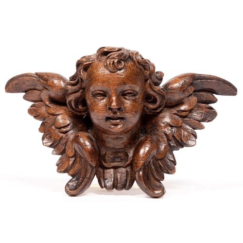 813 - A carved oak cherub's head applique in 17th c style, 29cm l, bears collection labels... 