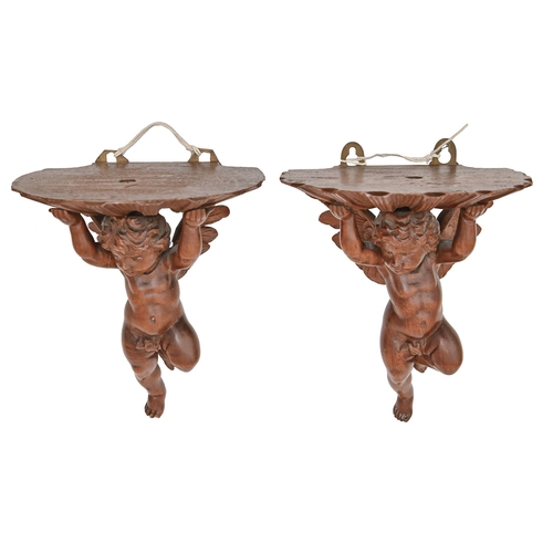 922 - A pair of Continental carved walnut wall brackets, in the form of winged cherubs, early 20th c, 19cm... 