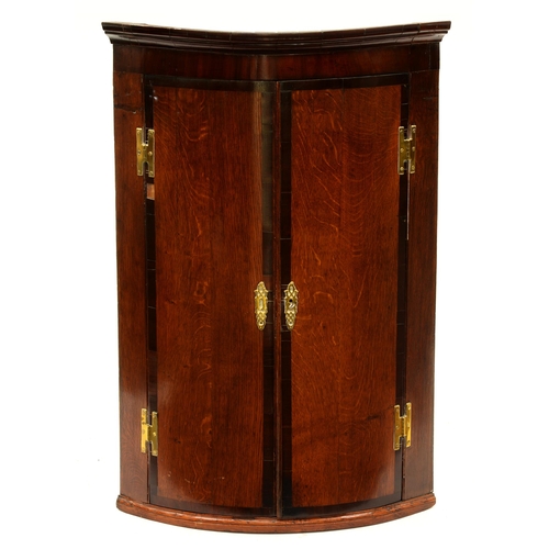 1197 - A George III oak and cross banded wall hanging corner cupboard, 98cm h; 46 x 67cm