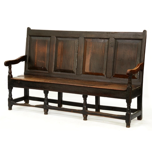 1218 - A George III oak settle with four raised and fielded panels to the back, draped arms and boarded sea... 