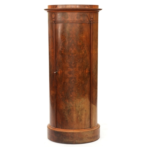 1227 - A Northern European Biedermeier style mahogany cupboard, 19th c, of oval section, the curved door is... 