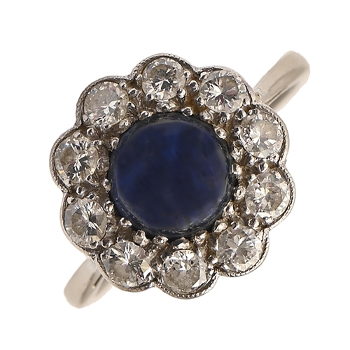 160 - A sapphire and diamond ring, the larger central sapphire en cabochon, in platinum, head 14mm diam, 4... 