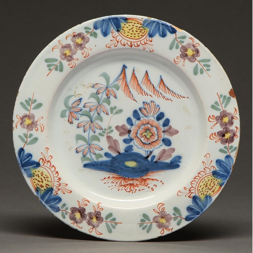 431 - An English Delftware plate, c1770, painted with a flower and tree, 22.5cm diam